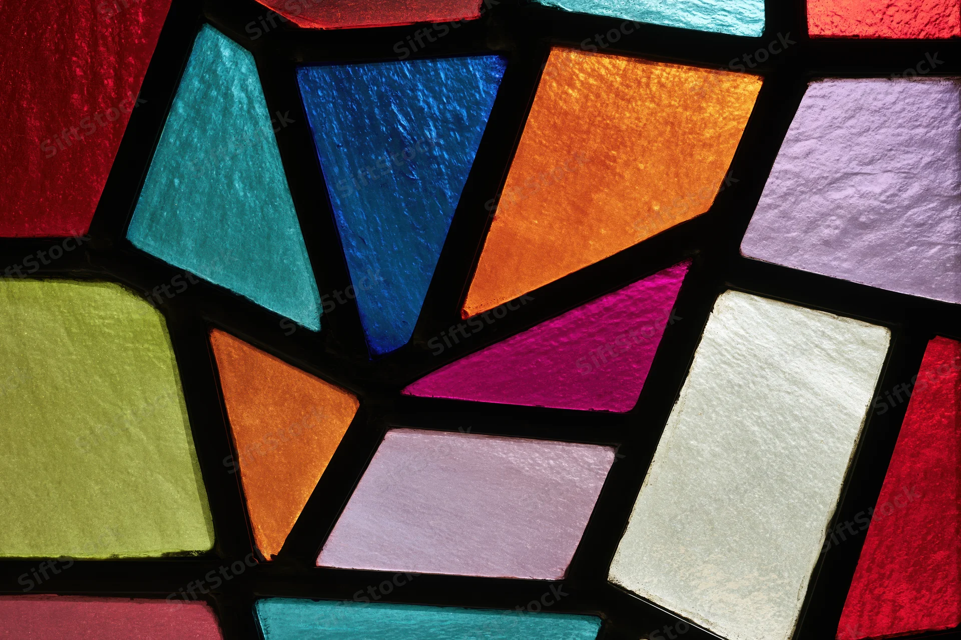 Close-up of a stained glass window with colorful geometric glass pieces arranged in a mosaic pattern
