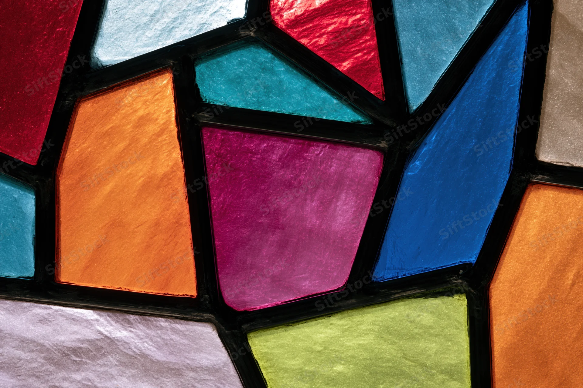 Close-up of a stained glass window with colorful geometric shapes arranged in a mosaic pattern