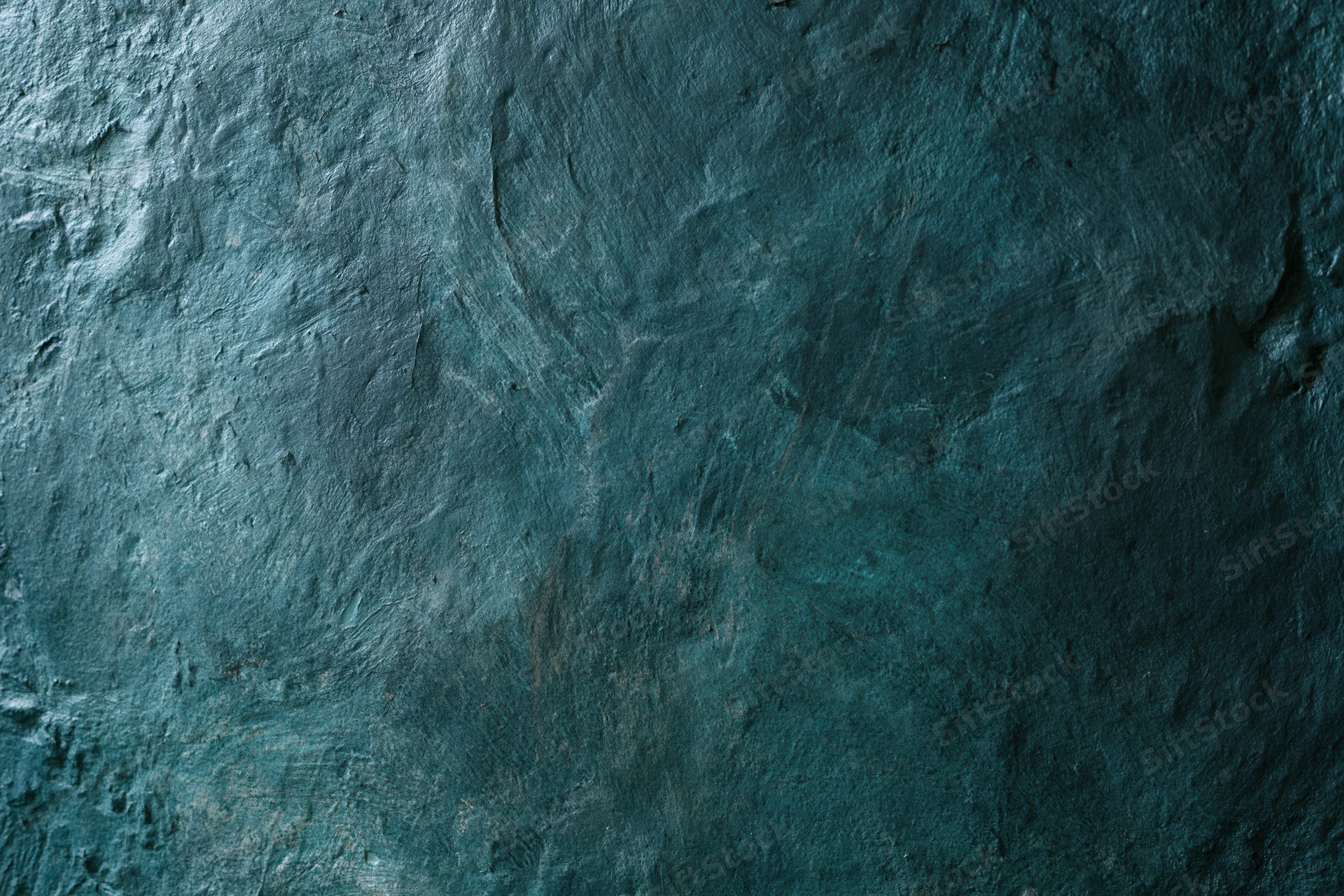 Close-up of a weathered painted wall surface with textured blue-gray finish