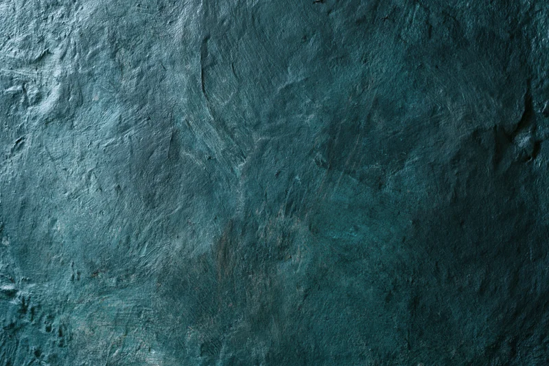 Close-up of a weathered painted wall surface with textured blue-gray finish