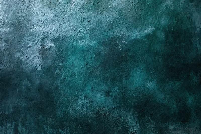 Weathered painted wall surface with textured blue-green finish showing signs of aging and wear