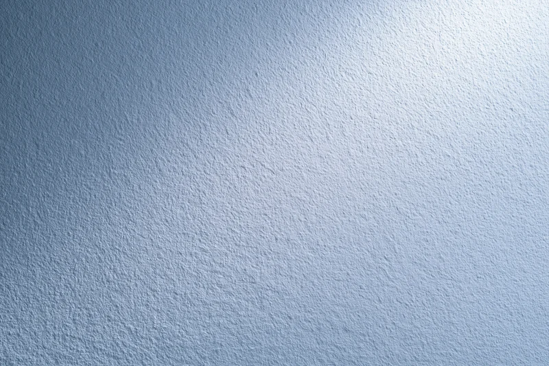 Close-up of a matte white painted wall with a soft blue gradient and even lighting