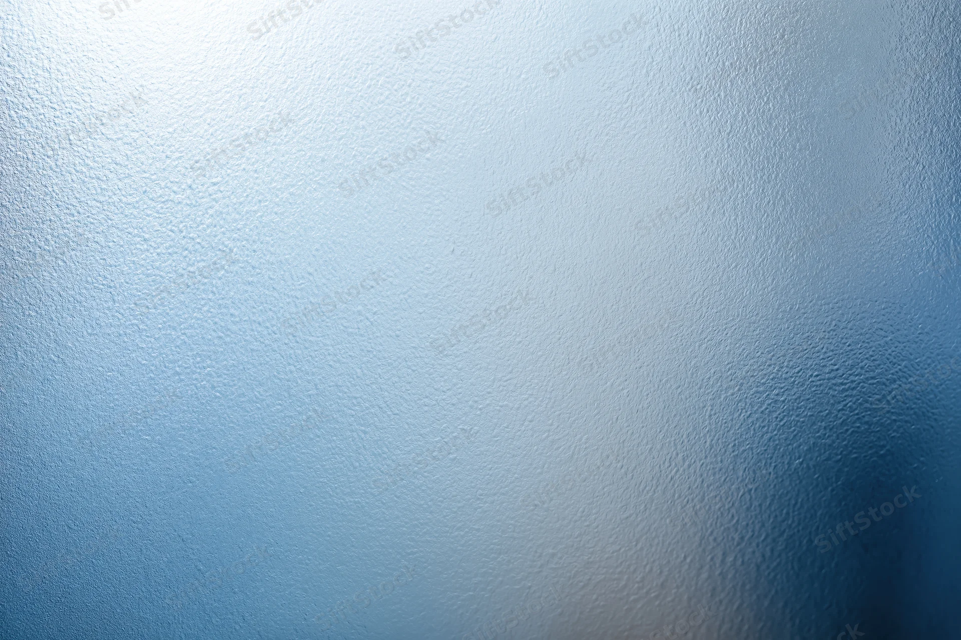 Frosted textured glass surface in close-up flat view with blue gradient and soft light diffusion