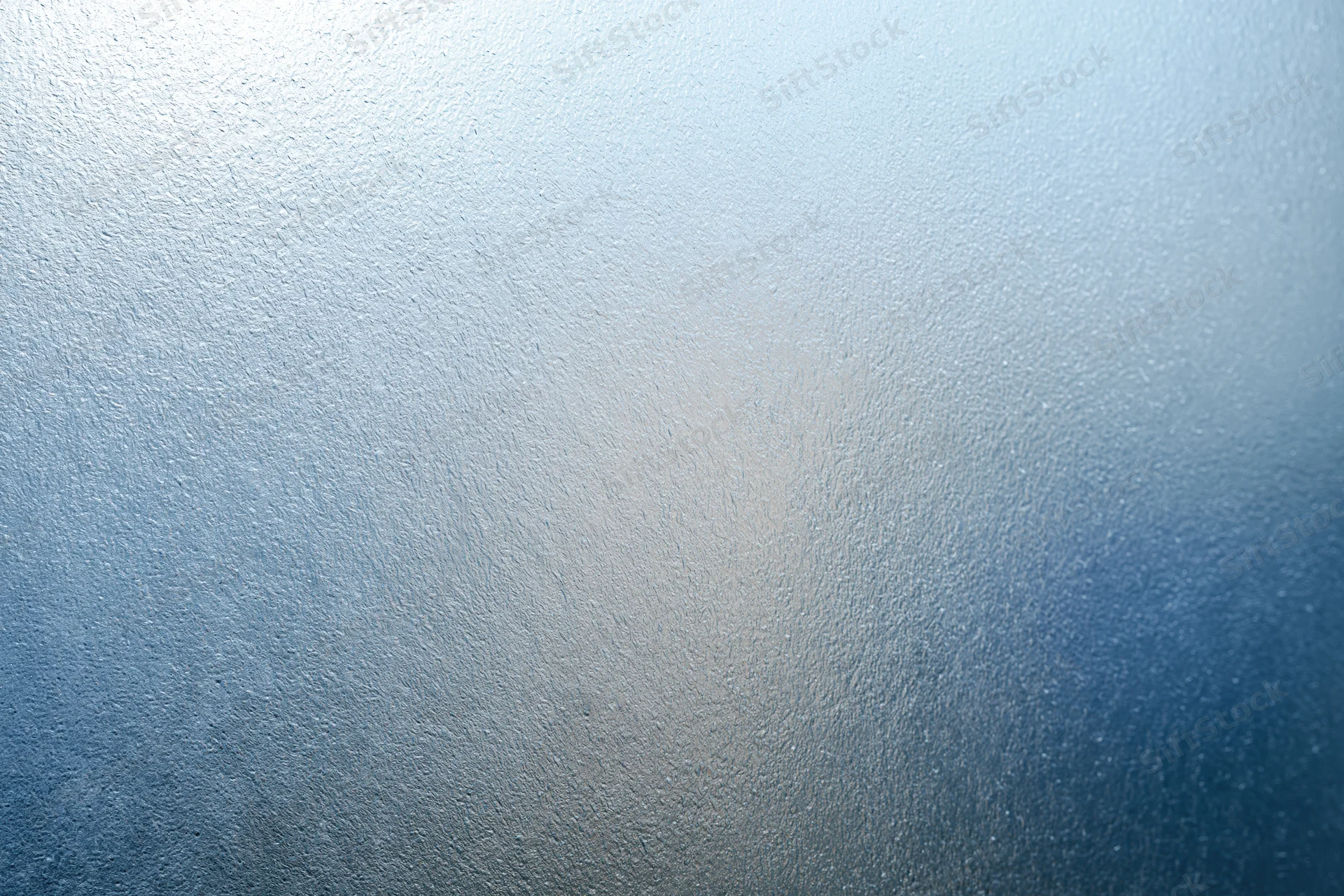 Frosted textured glass surface in close-up flat view with blue gradient and diffused light