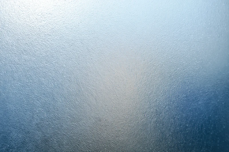 Frosted textured glass surface in close-up flat view with blue gradient and diffused light