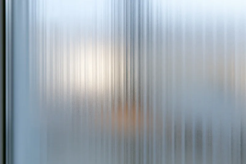 Ribbed frosted glass panel filling the frame with vertical texture and diffused light