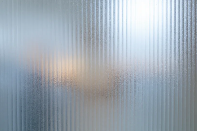Ribbed frosted glass panel filling the frame with vertical texture and diffused light