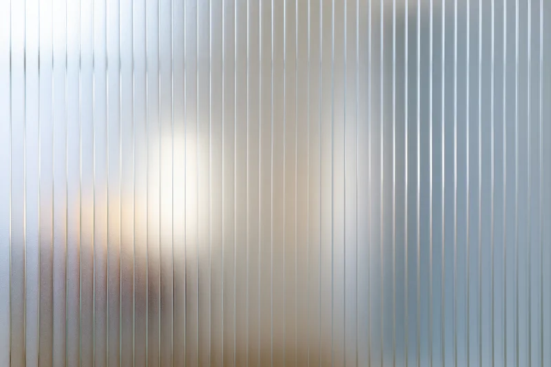 Ribbed frosted glass panel filling the frame with vertical lines and diffused light