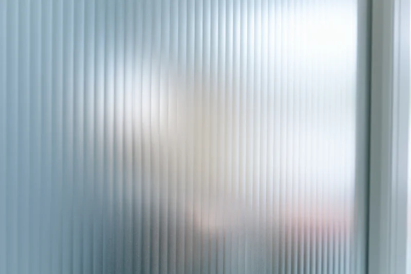 Ribbed frosted glass panel filling the frame with vertical lines and diffused light