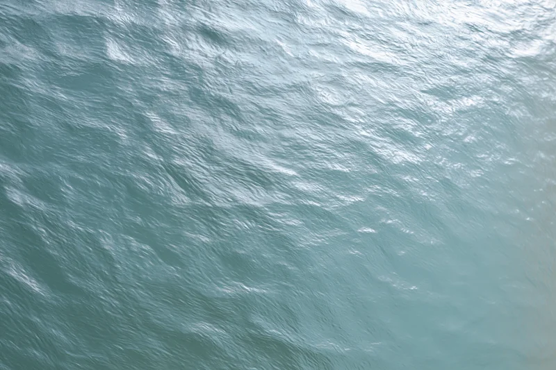 Textured water surface with gentle ripples and light reflections, frosted glass panel effect