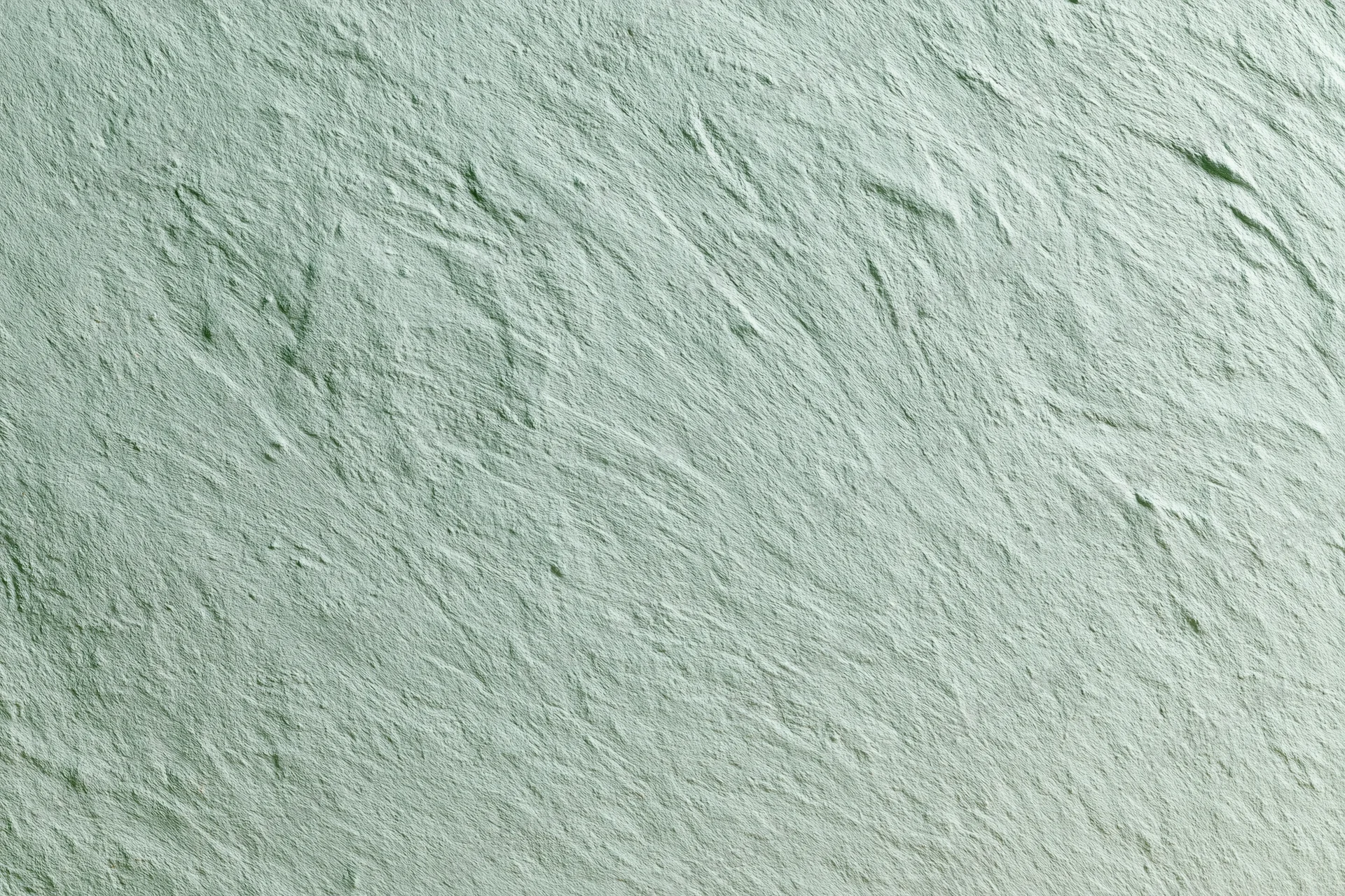 Close-up of a matte painted concrete wall surface with rough texture and green-gray tone