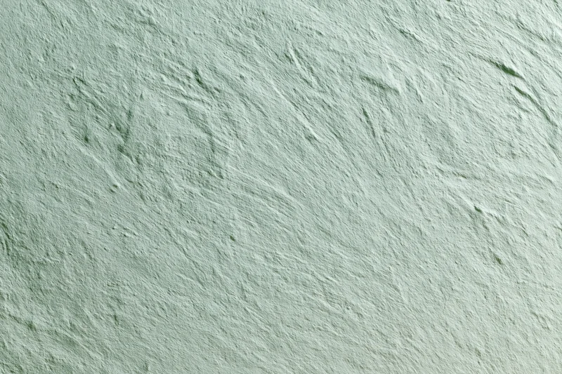 Close-up of a matte painted concrete wall surface with rough texture and green-gray tone