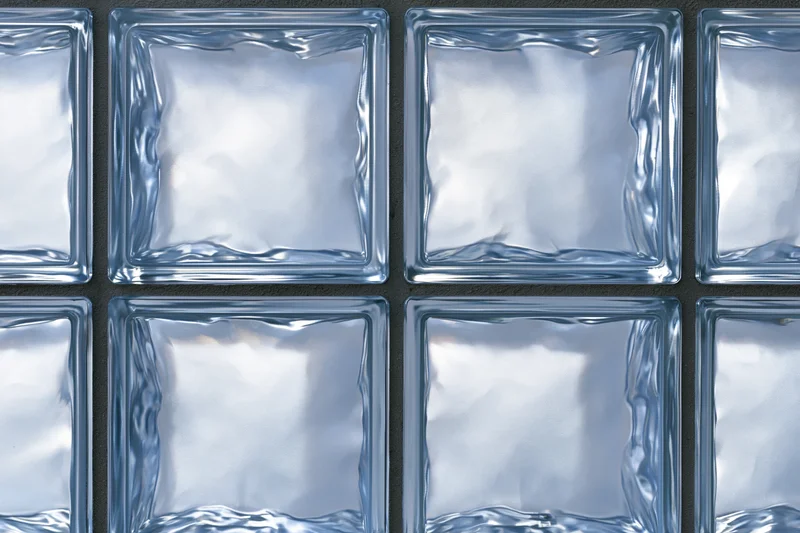 Close-up of a glass block wall arranged in a grid pattern with transparent square panels set in a dark frame