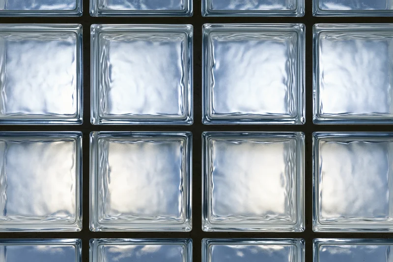 Close-up of a glass block wall arranged in a grid pattern with dark grout lines