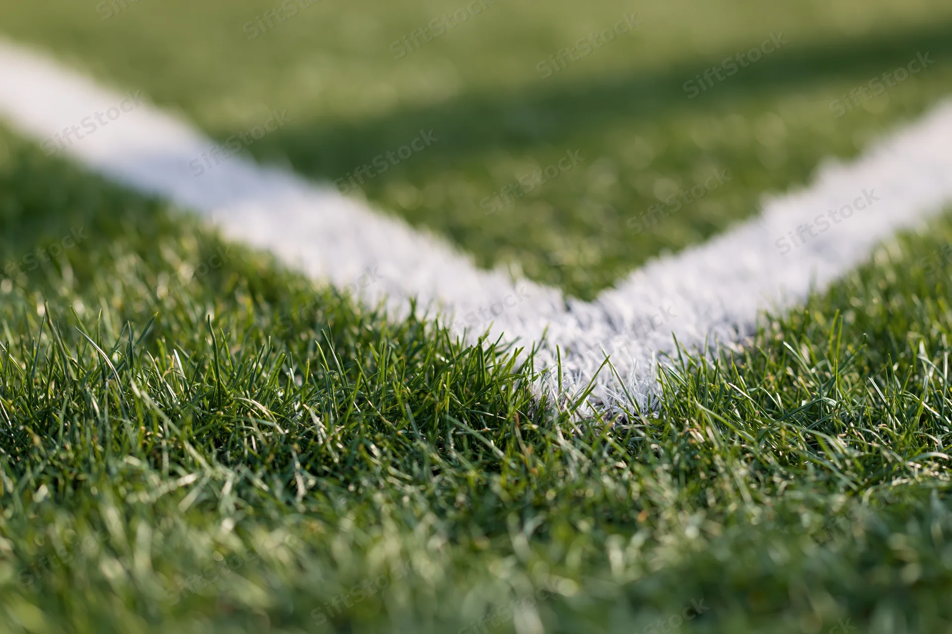 Close-up ground-level view of white corner marking lines on a green football pitch grass surface