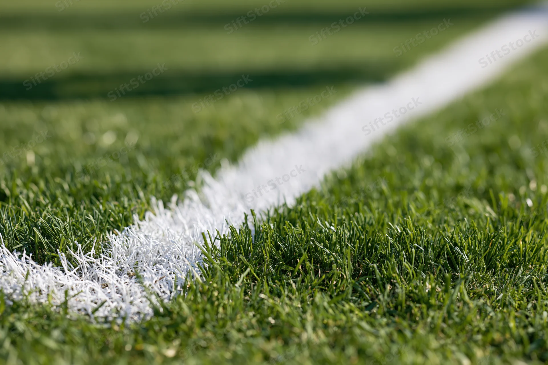 Close-up of white corner line marking on a green football pitch grass surface