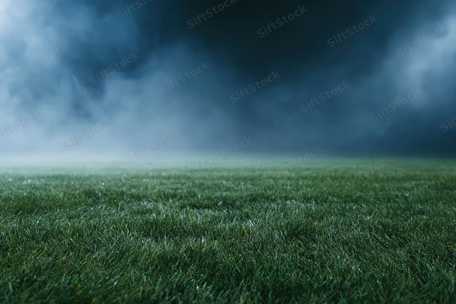 Close-up ground-level view of a professional football pitch under stormy sky