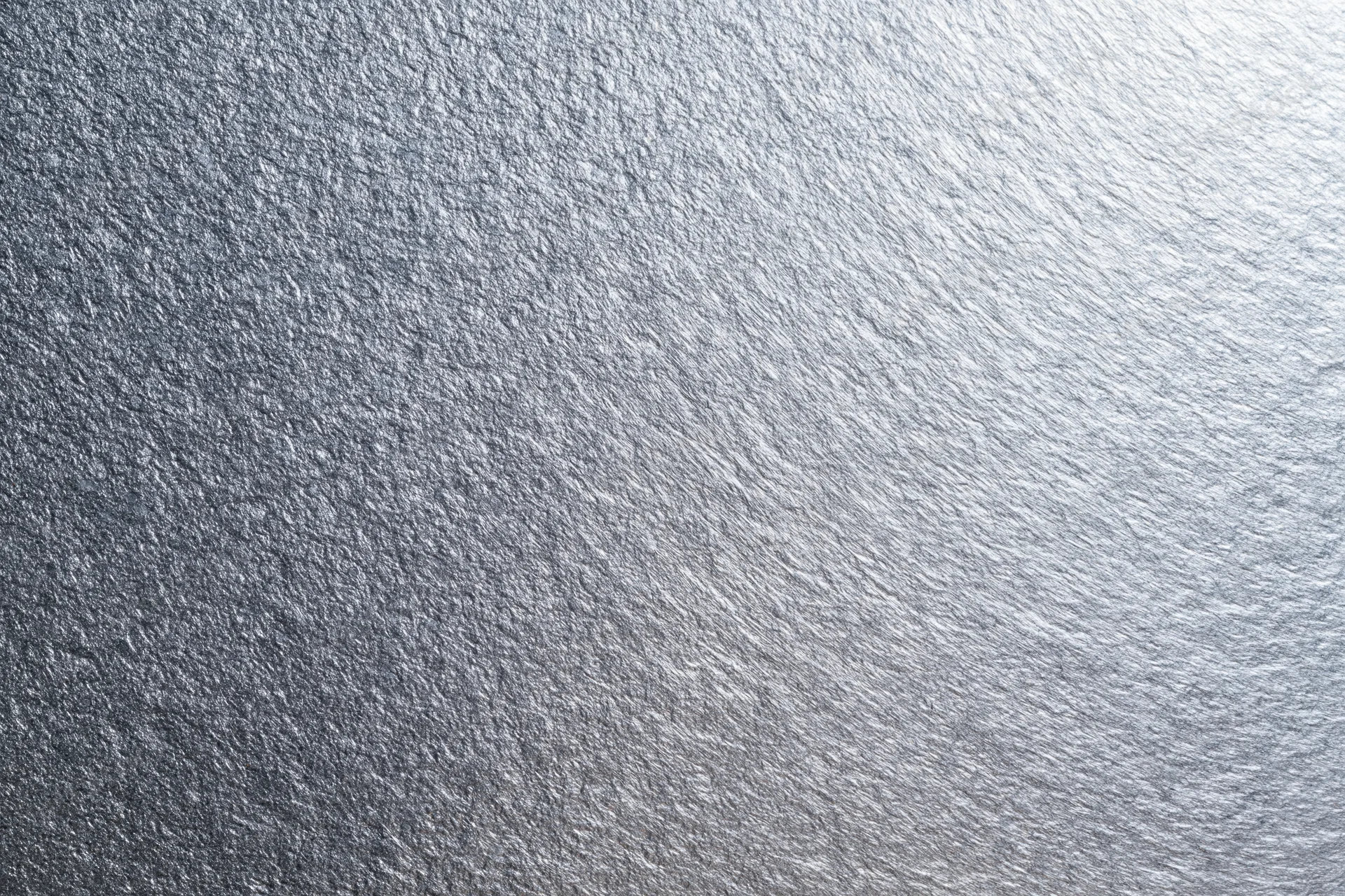 Close-up of brushed metallic silver surface showing fine texture and reflective grain
