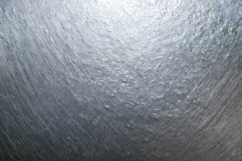 Close-up of brushed silver metal surface showing fine grain texture and reflective sheen