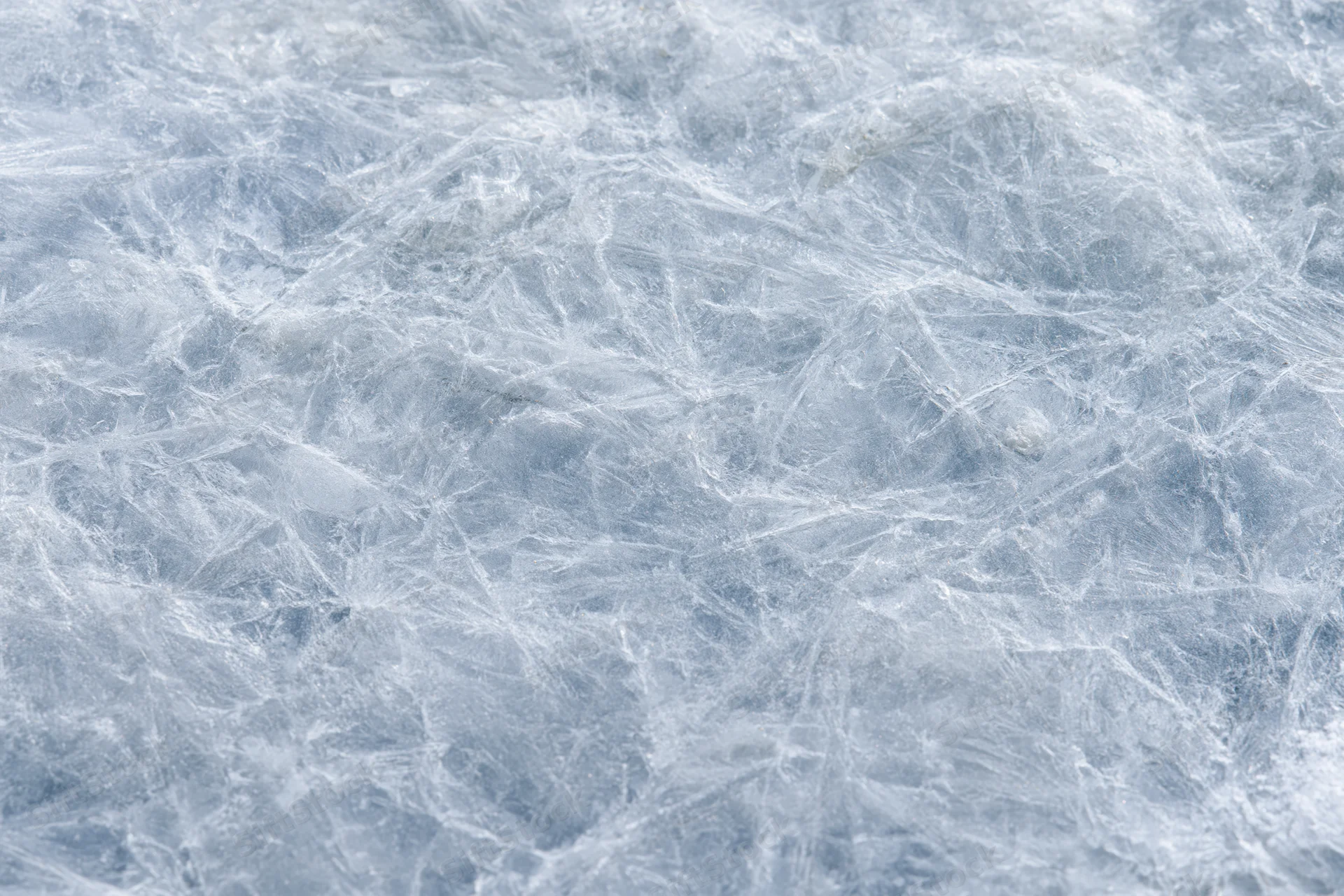Close-up of a cracked frozen ice surface showing intricate web-like patterns across the frame