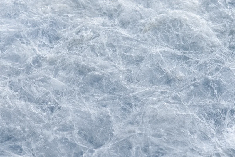 Close-up of a cracked frozen ice surface showing intricate web-like patterns across the frame