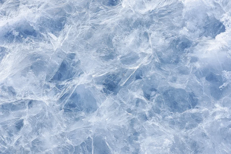 Close-up of a frozen ice surface with visible cracks and crystal formations filling the frame