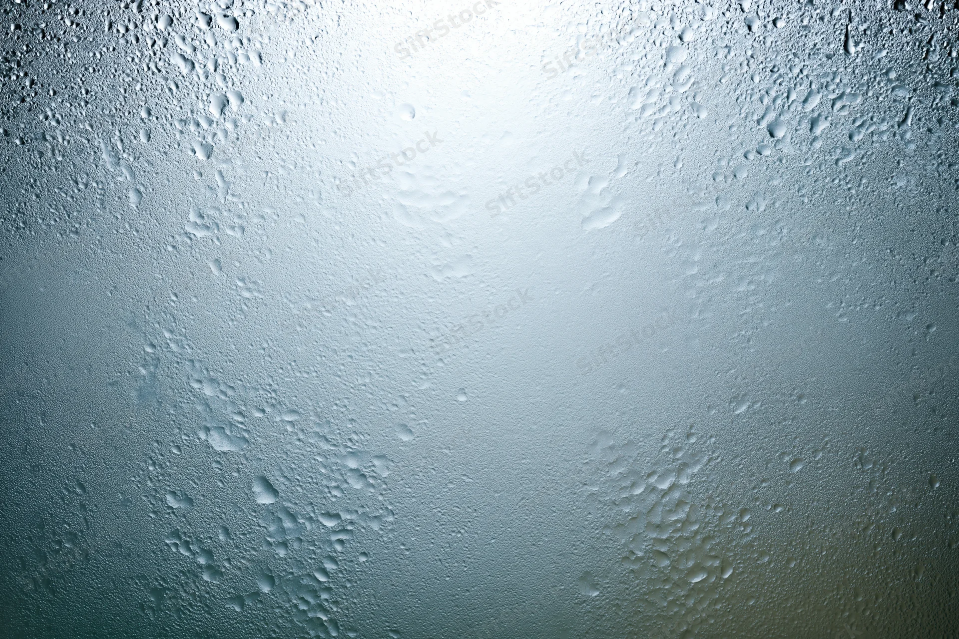 Fogged glass surface covered in fine water droplets with light reflection