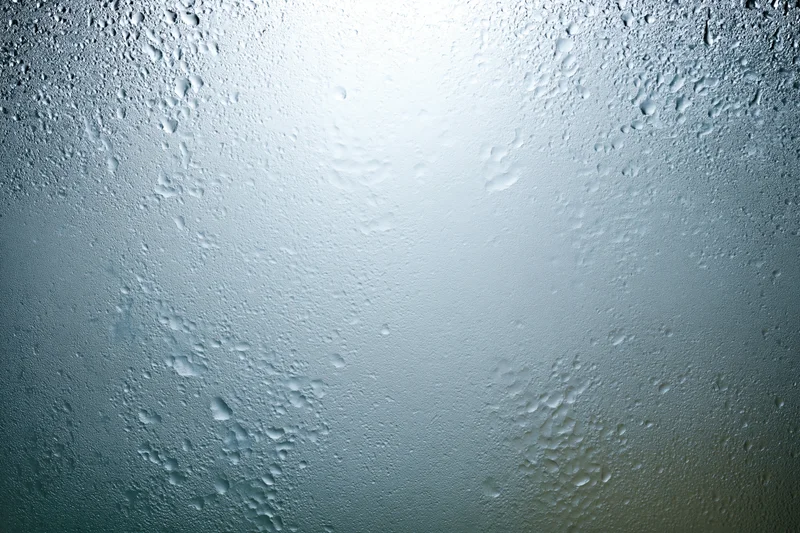 Fogged glass surface covered in fine water droplets with light reflection