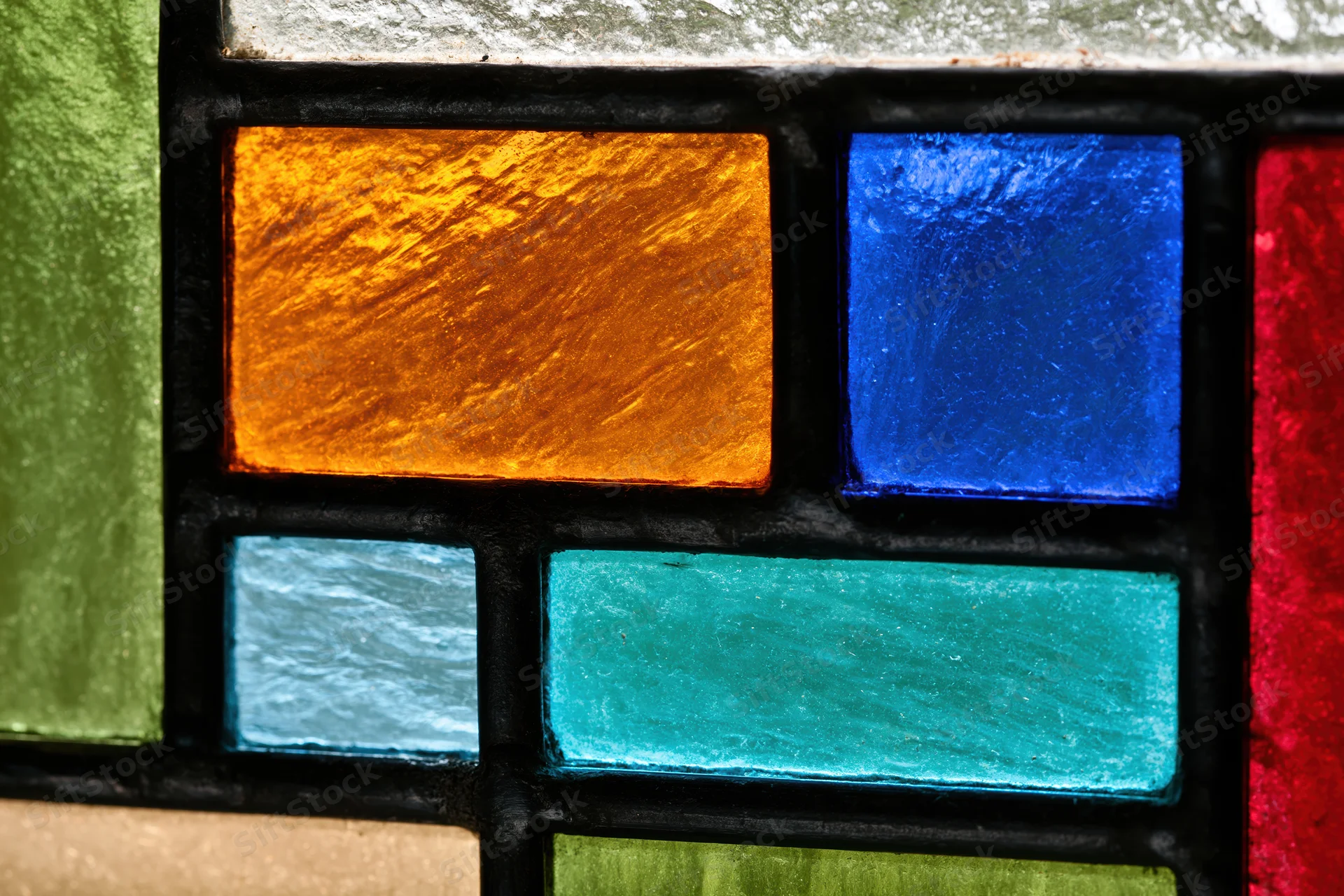 Close-up of a geometric stained glass window panel with colored glass pieces arranged in a grid pattern