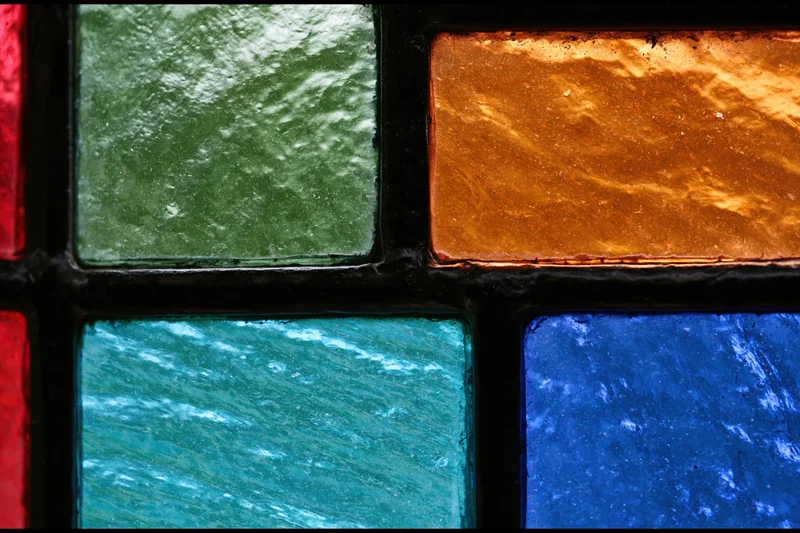 Close-up of a stained glass window panel with geometric shapes and vibrant colored glass arranged in a grid pattern