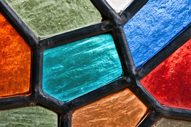 Close-up of a stained glass window panel with geometric shapes and vibrant colors arranged in a leaded pattern