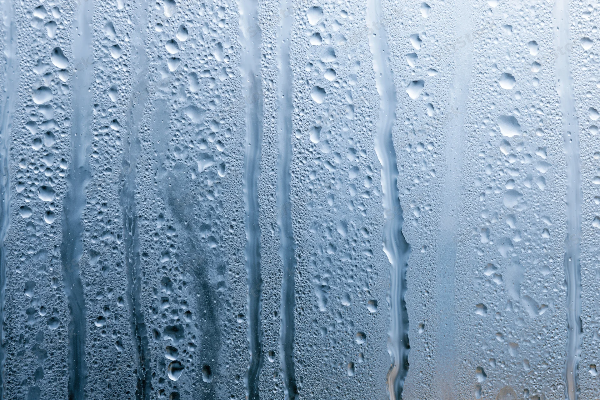Wet glass window surface with water droplets and streaks from condensation