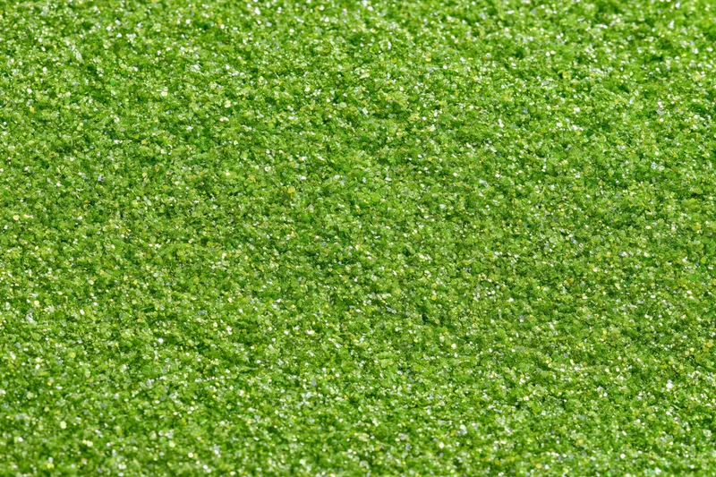 Bright green glitter texture filling the frame in a close-up macro view