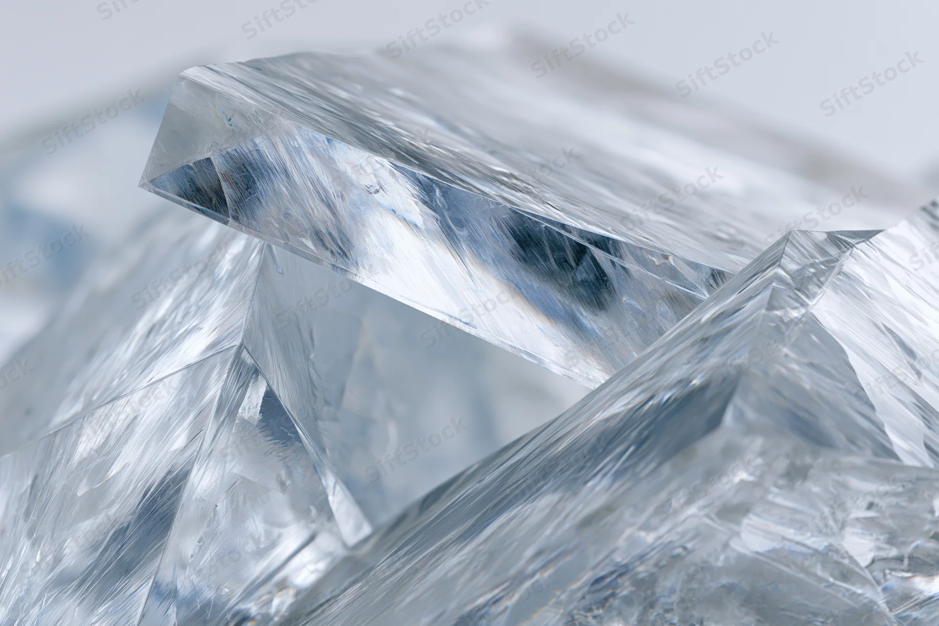 Fractured clear acrylic shard in close-up macro view with sharp edges and light reflections