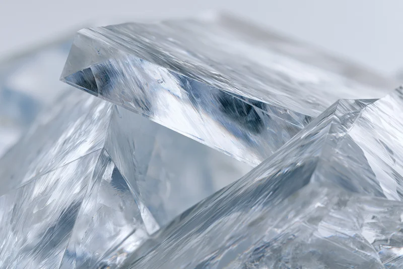 Fractured clear acrylic shard in close-up macro view with sharp edges and light reflections