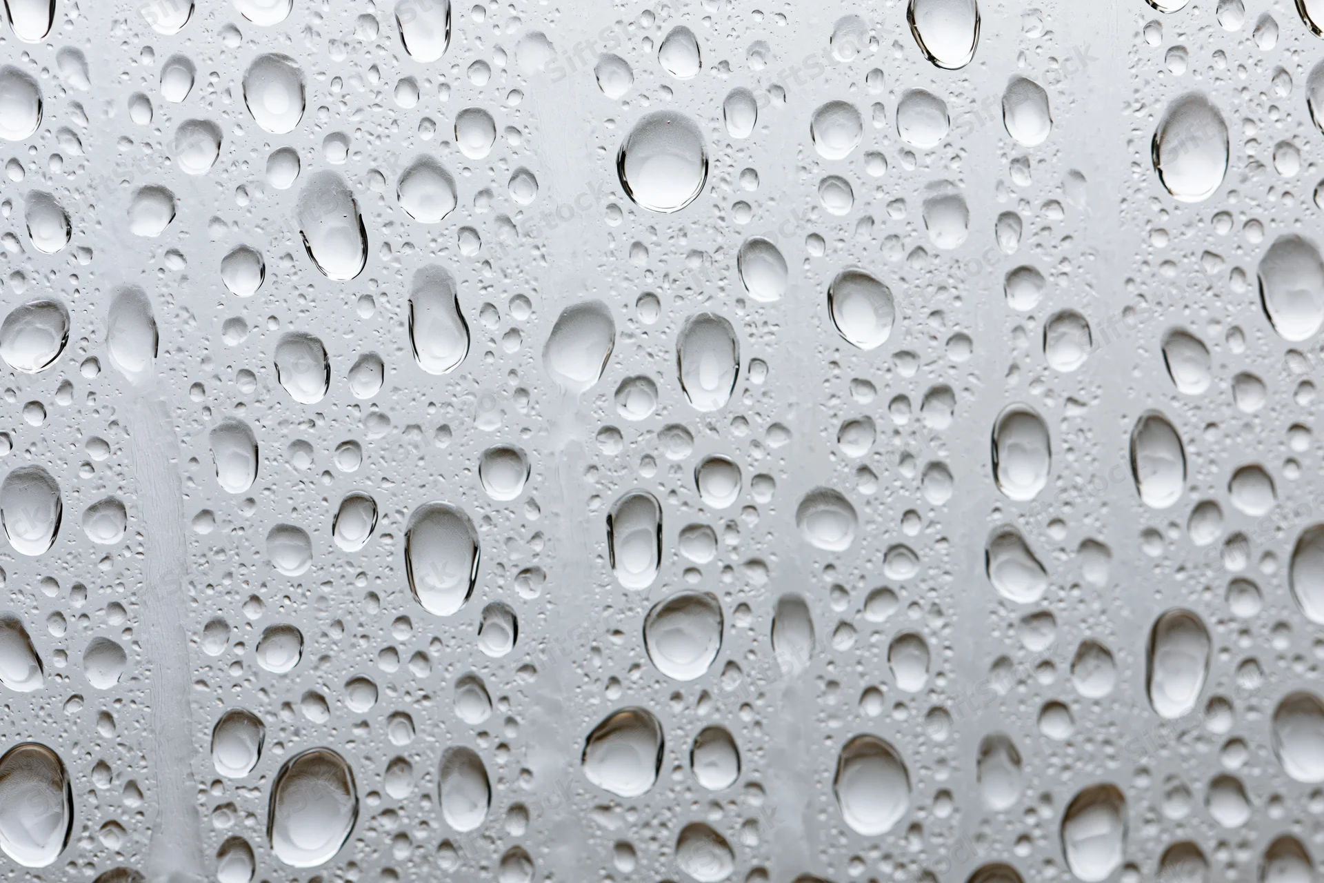 Water droplets clinging to a glass surface in a close-up macro view