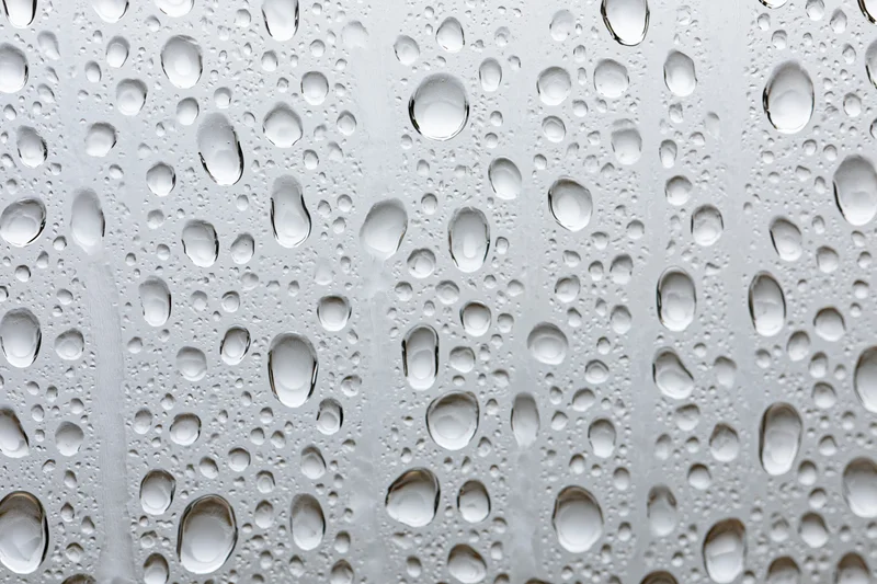 Water droplets clinging to a glass surface in a close-up macro view
