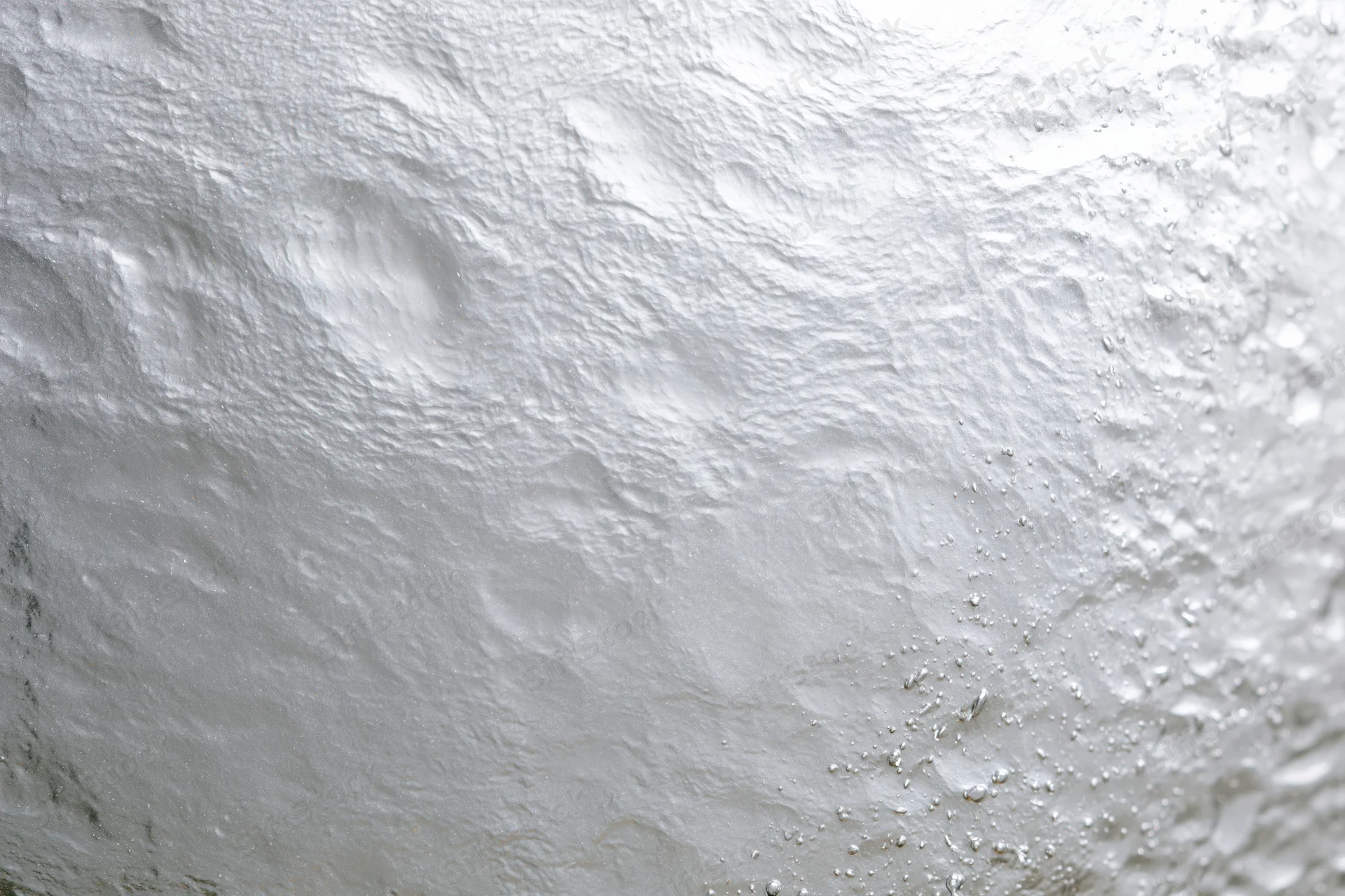Wet glass surface covered in water droplets with condensation and light reflections