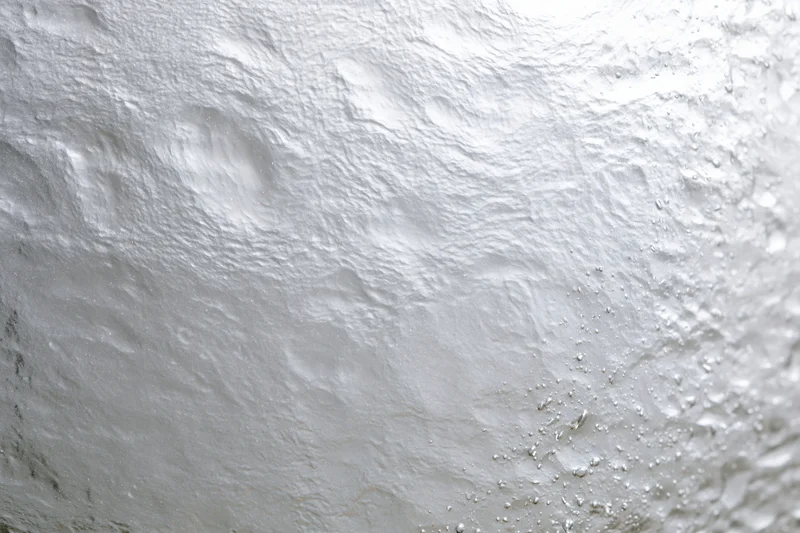 Wet glass surface covered in water droplets with condensation and light reflections