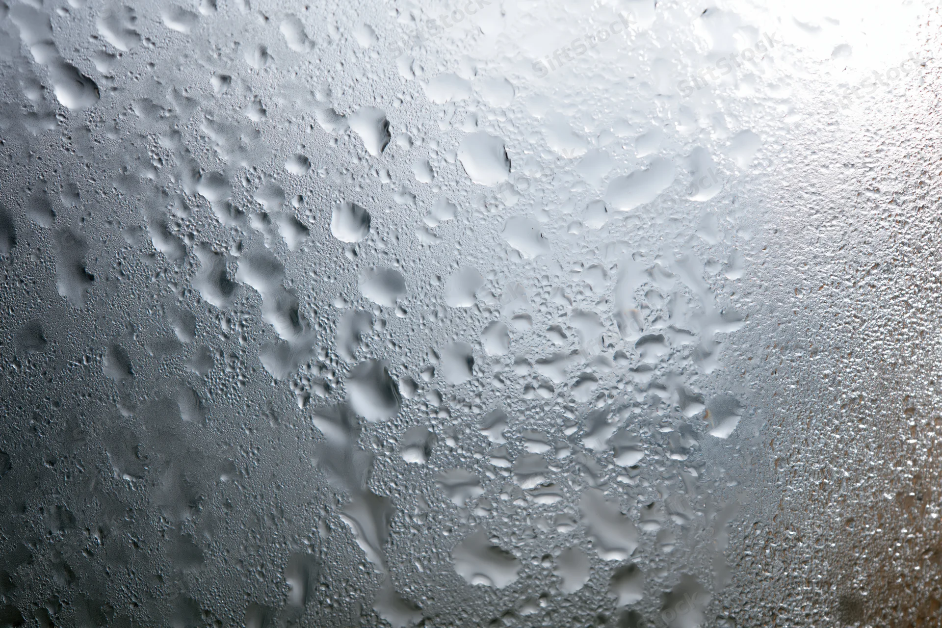 Fogged glass window surface covered in dense water droplets and condensation