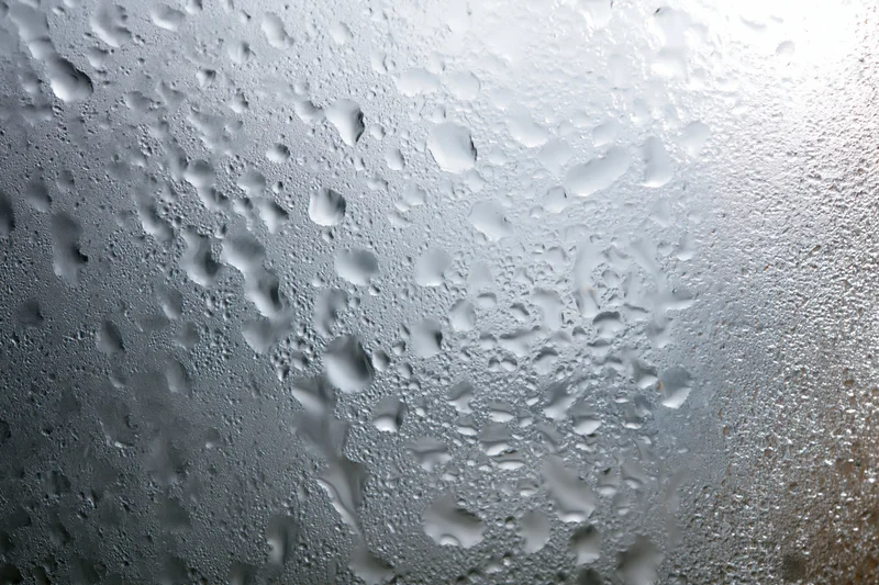 Fogged glass window surface covered in dense water droplets and condensation