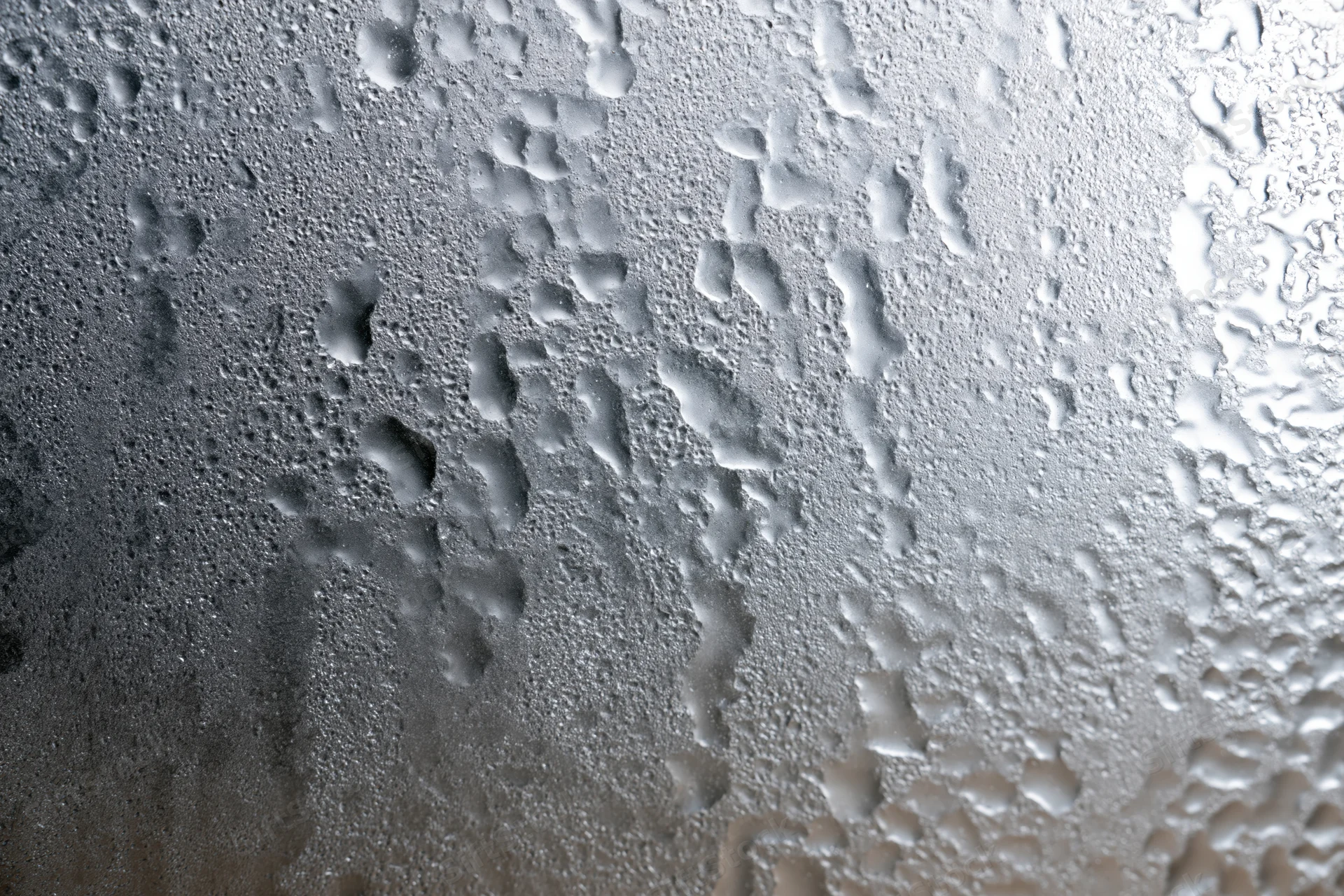 Fogged glass window surface covered in dense water droplets and condensation