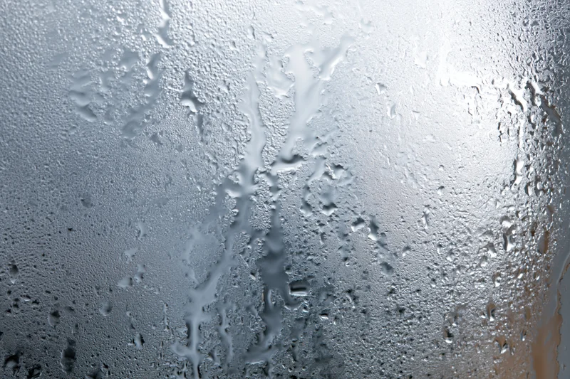 Fogged glass window covered in water droplets and condensation streaks