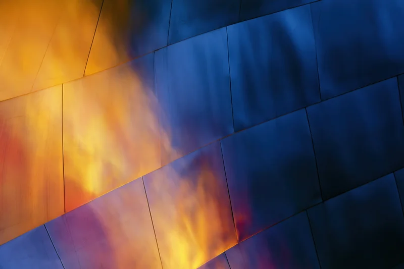 Curved metal panels forming a reflective architectural surface with blue and orange light gradients