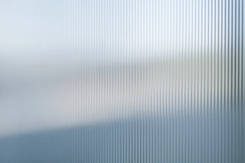 Close-up of ribbed frosted glass panel with vertical texture and diffused light