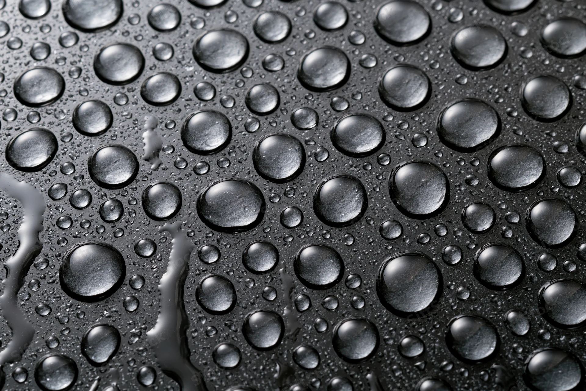 Water droplets scattered across a dark wet glass surface
