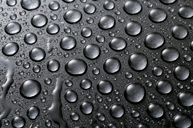 Water droplets scattered across a dark wet glass surface