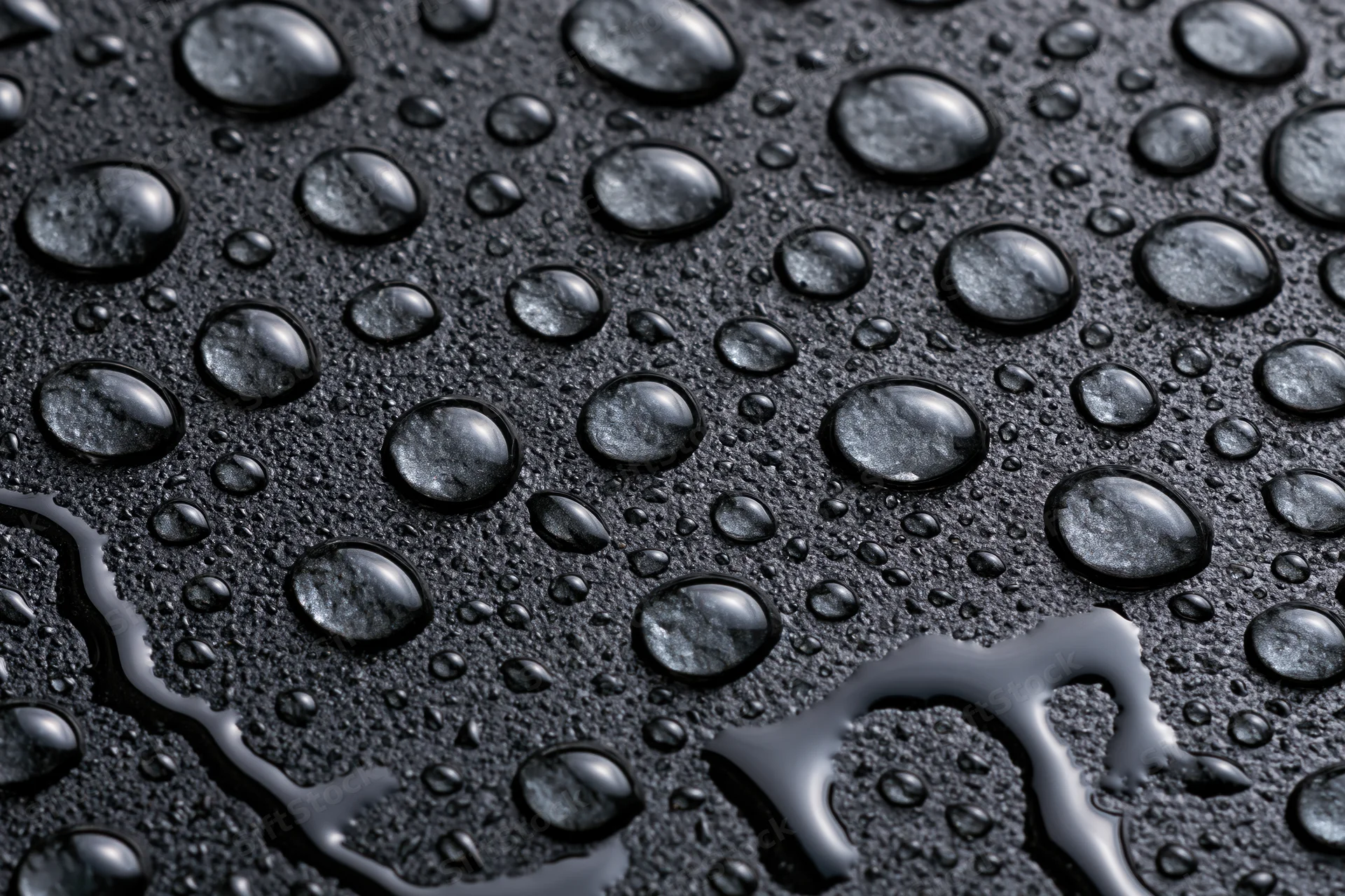 Water droplets scattered across a dark wet glass surface