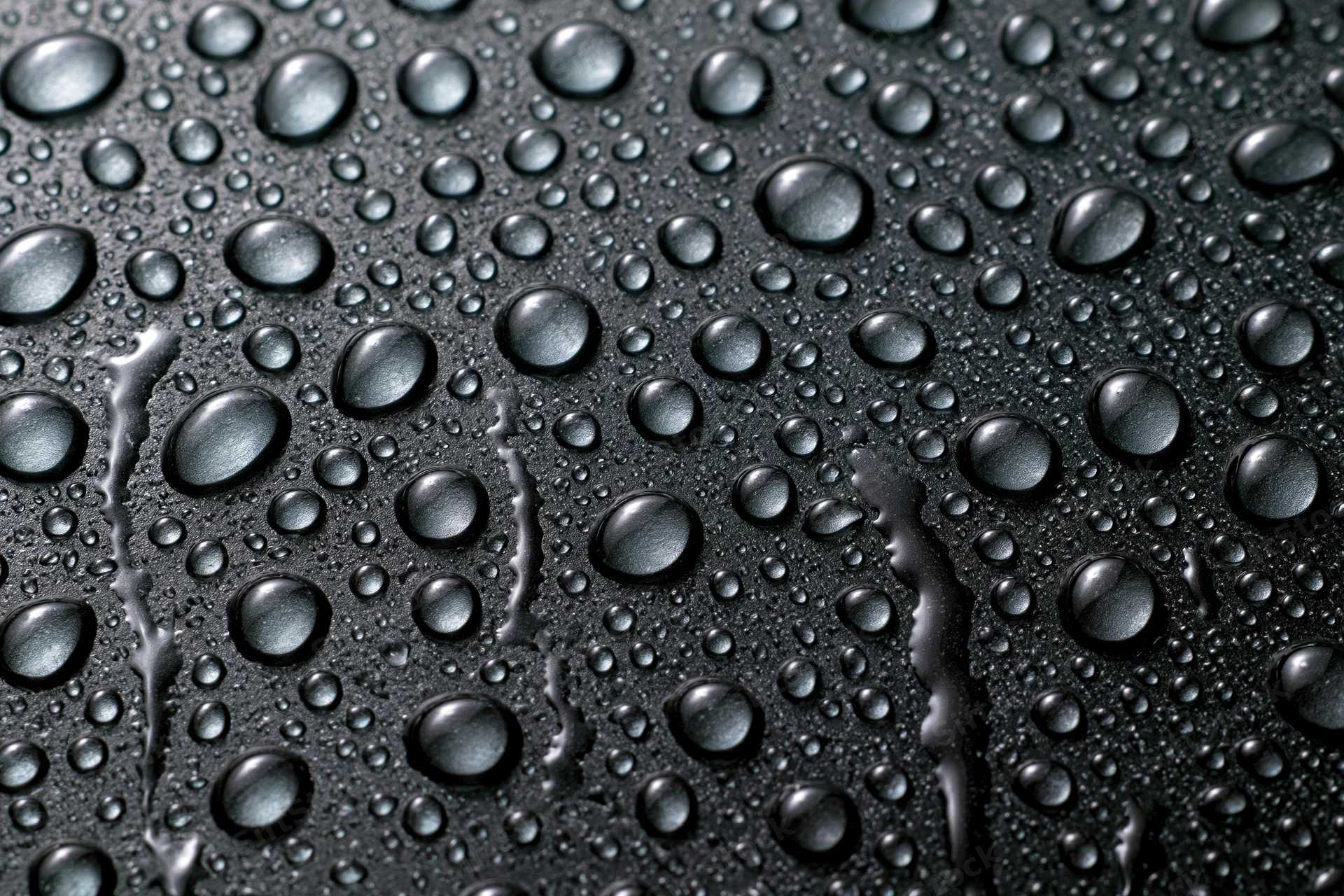 Water droplets scattered across a dark wet glass surface