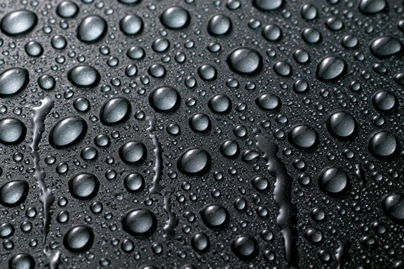 Water droplets scattered across a dark wet glass surface